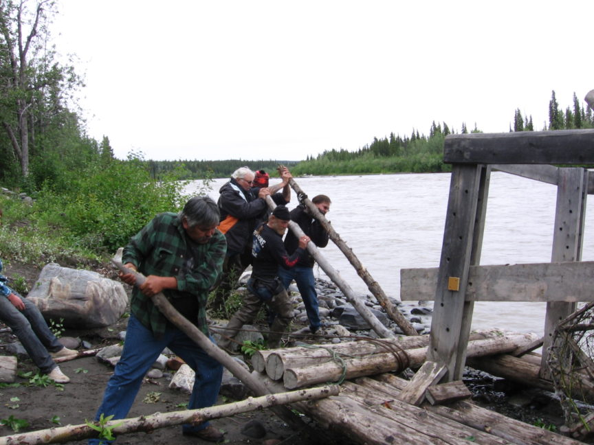 Members of a Euro-American motorcycle club work alongside citizens of the Athabascan Nation to launch a fish wheel in the Copper River, Alaska.